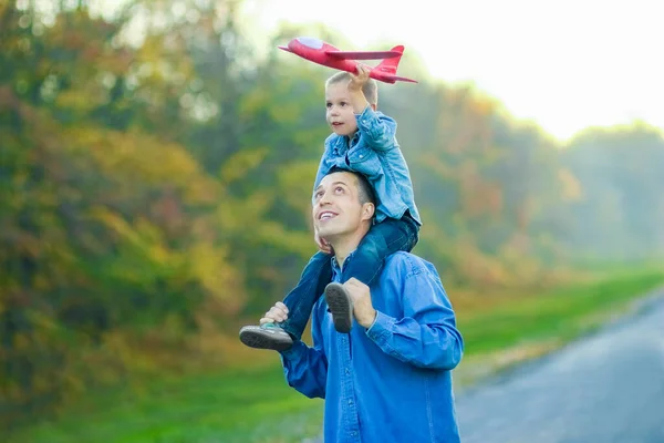 幸せな親は 自然旅行で公園内の子供と飛行機と一緒に道路に沿って歩く — ストック写真