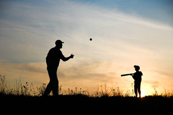 Happy child with parent playing baseball concept family in park in nature
