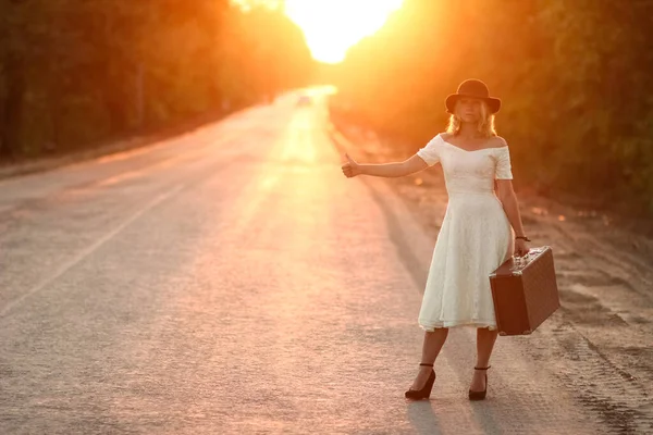 ヴィンテージの女の子の帽子にスーツケースのヒッチハイク — ストック写真