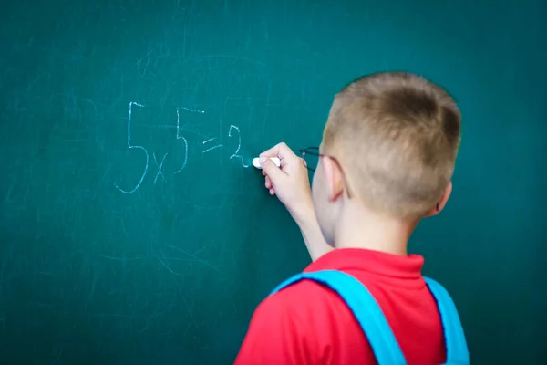 快乐的孩子站在黑板前 背着上学用的背包 戴着眼镜 — 图库照片