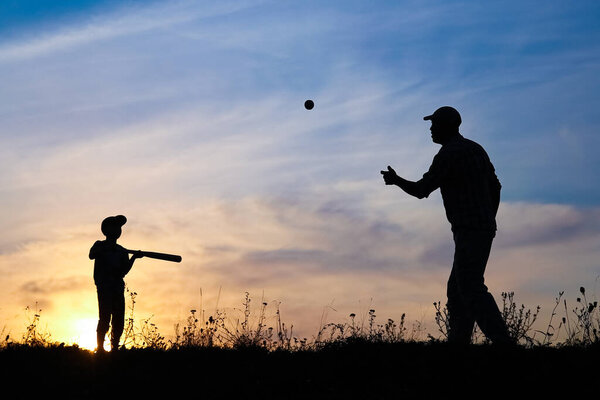 Счастливый ребенок с родителями играет в бейсбол в парке на природе