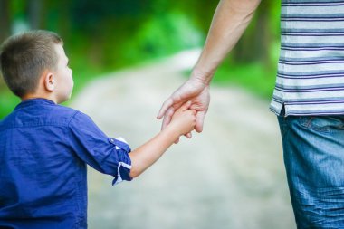 Mutlu çocuk ve ebeveynin parktaki gezinin doğasında elleri var.