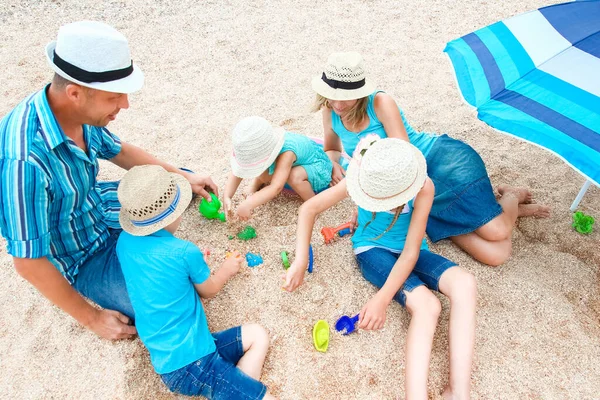 砂の上で海の岸で遊ぶ幸せな家族 — ストック写真