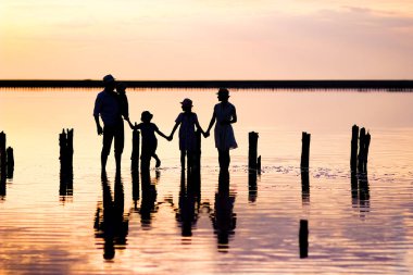 Denizde mutlu bir aile silueti. Doğada yansıması var.