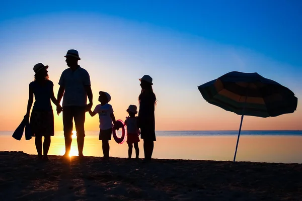 自然の中で旅行のシルエットで日没で海によって幸せな家族 — ストック写真
