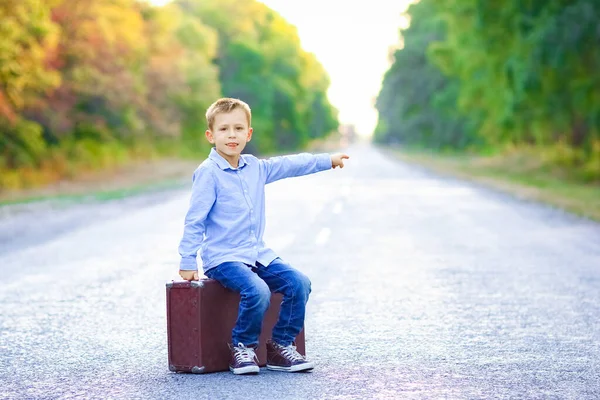 stock image Happy child with a suitcase on the road in the park travel