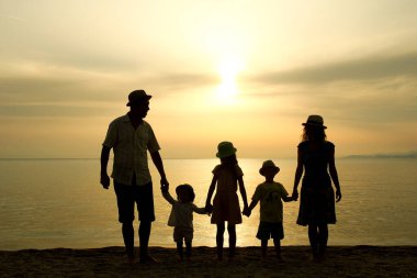 Doğada mutlu bir aile deniz kenarında bir siluette