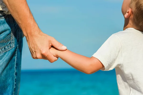 幸せなお父さんはギリシャの海のそばで子供の手を握ってる — ストック写真