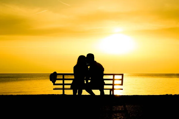 旅のシルエットの自然の海の上のベンチで幸せなカップル — ストック写真