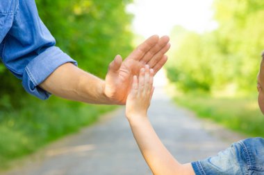 Hands of a happy parent and child in nature in the travel park