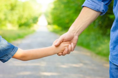 Hands of a happy parent and child in nature in the travel park