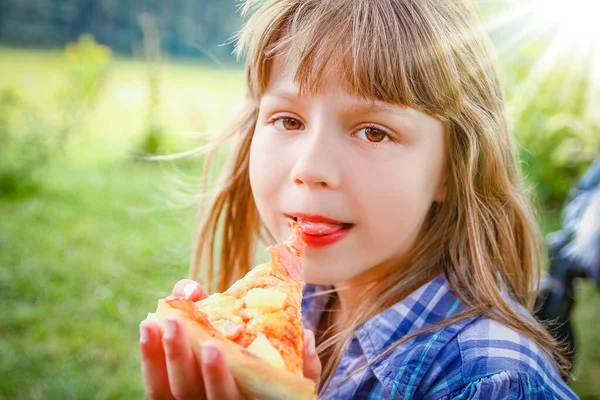 公園の芝の自然でおいしいピザを食べる子 — ストック写真