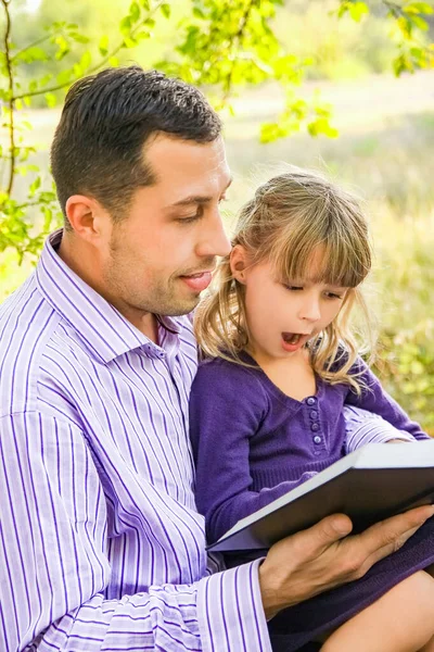 一个年轻的父亲和一个小女儿读圣经 — 图库照片
