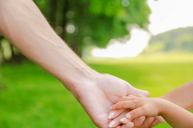 Mutlu aile ve çocuk parkta el ele tutuşuyor.