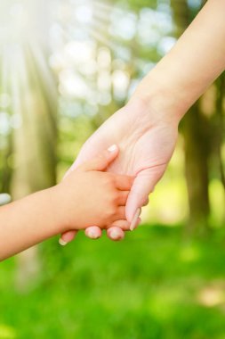 Mutlu aile ve çocuk parkta el ele tutuşuyor.