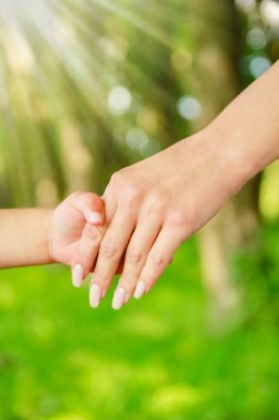 Mutlu aile ve çocuk parkta el ele tutuşuyor.