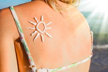 Sırtında güneş, doğada deniz kenarında mutlu bir kız.