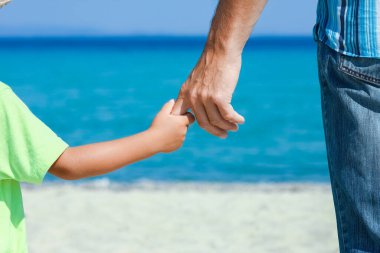 Mutlu bir ebeveynin elleri ve deniz kıyısındaki çocuk doğa yolculuğunda.