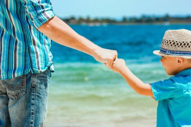 Mutlu baba, Yunan Denizi kıyısında bir çocuğun elini tutuyor.