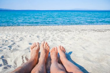 Hafta sonu doğa gezisinde deniz kenarında mutlu bir ailenin ayakları.