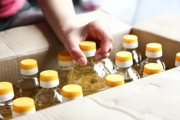 Många Flaskor Solrosolja Låda Med Människor Hand Bakgrund — Stockfoto