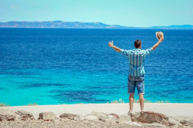 Hafta sonu doğa gezisinde deniz kenarında mutlu bir adam.