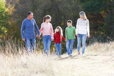 Mutlu aile sonbahar konseptiyle parkta birlikte yürüyor. Mutluluk.