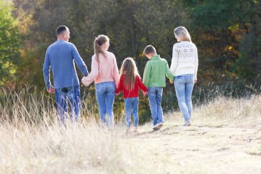 Mutlu aile sonbahar konseptiyle parkta birlikte yürüyor. Mutluluk.