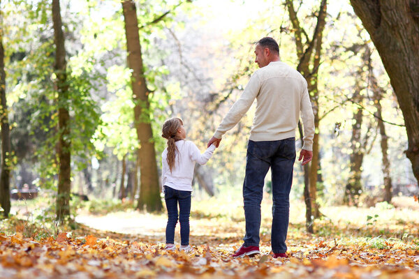 father walks with child in the park in autumn concept family together