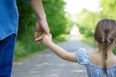 Hands of a happy parent and child in nature in the travel park