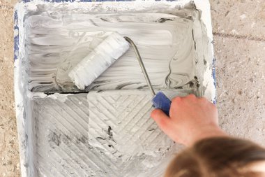 Elinde boya olan bir silindir ev onarımı.