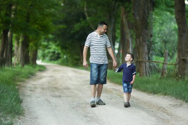 Mutlu çocuk ve ebeveynin parktaki gezinin doğasında elleri var.