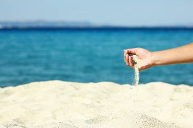 Hafta sonu doğa seyahatinde deniz kenarına kum döken eller.