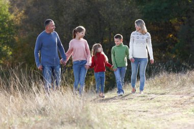 Mutlu aile sonbahar konseptiyle parkta birlikte yürüyor. Mutluluk.