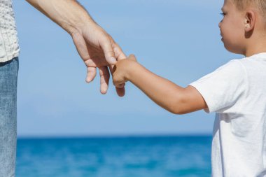 Mutlu baba, Yunan Denizi kıyısında bir çocuğun elini tutuyor.