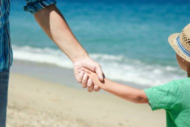 Mutlu bir ebeveynin elleri ve deniz kıyısındaki çocuk doğa yolculuğunda.