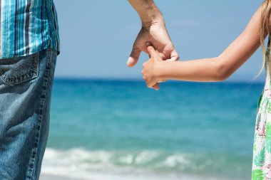 Mutlu bir ebeveynin elleri ve deniz kıyısındaki çocuk doğa yolculuğunda.