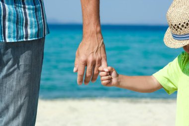 Mutlu bir ebeveynin elleri ve deniz kıyısındaki çocuk doğa yolculuğunda.