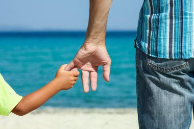 Mutlu bir ebeveynin elleri ve deniz kıyısındaki çocuk doğa yolculuğunda.