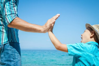 Mutlu bir ebeveynin ve çocuğun elleri doğa yolculuğunda deniz kenarında.