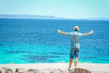 Hafta sonu doğa gezisinde deniz kenarında mutlu bir adam.
