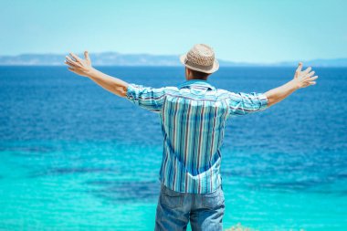 Hafta sonu doğa gezisinde deniz kenarında mutlu bir adam.