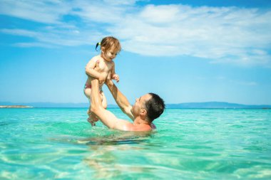 happy father and child playing in the sea in nature