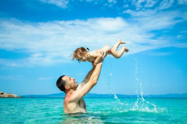 happy father and child playing in the sea in nature