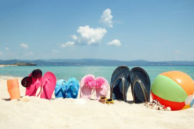 Sahildeki kumda güzel terlikler, doğa arka planında Yunan denizleri.