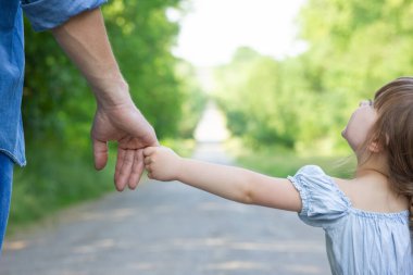 Hands of a happy parent and child in nature in the travel park