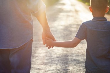 Hands of a happy parent and child in nature in the travel park