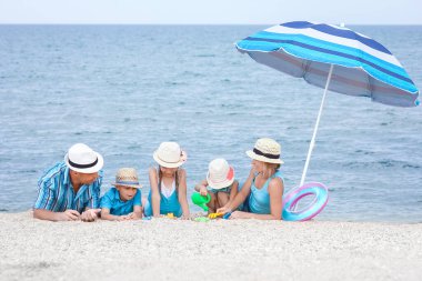 Sahilde kumsalda oynayan mutlu bir aile.