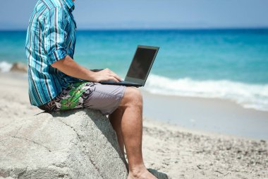 Happy man guy with laptop near the seashore weekend travel