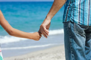 Mutlu bir ebeveynin elleri ve deniz kıyısındaki çocuk doğa yolculuğunda.